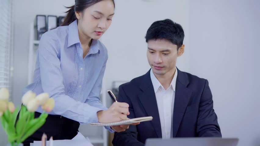 Two business women are sitting and talking in the office and discussing projects on laptops and graphs working together in the office.