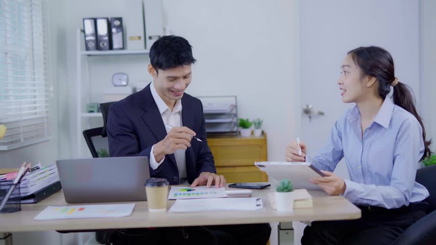 Two business women are sitting and talking in the office and discussing projects on laptops and graphs working together in the office.
