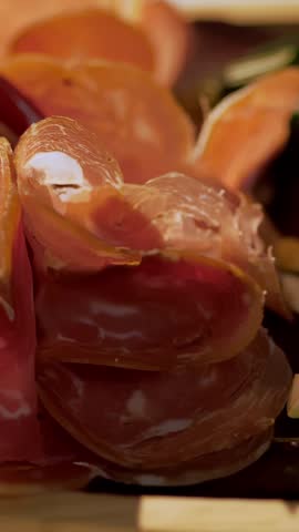 Meat appetizer. jamon. Delicious variety of meat appetizers, Prosciutto crudo or jamon meat with rosemary on serving wooden platter. The chef puts jamon on serving board.