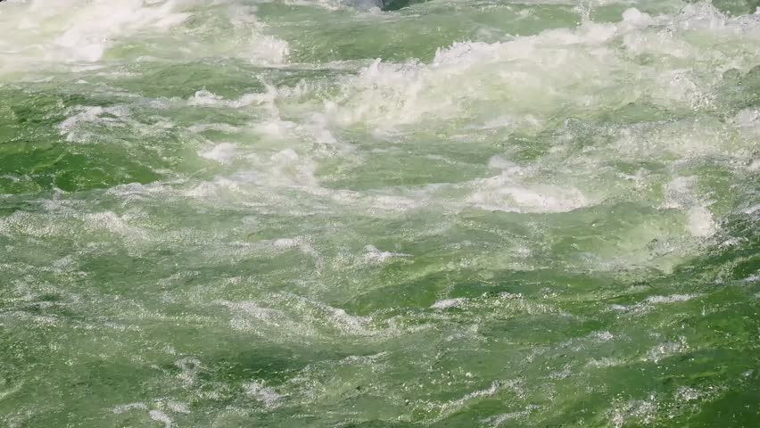 Close-up of fast whitewater rapids in Tacen, Slovenia, with green river waves, foam and strong current on a kayak slalom course.