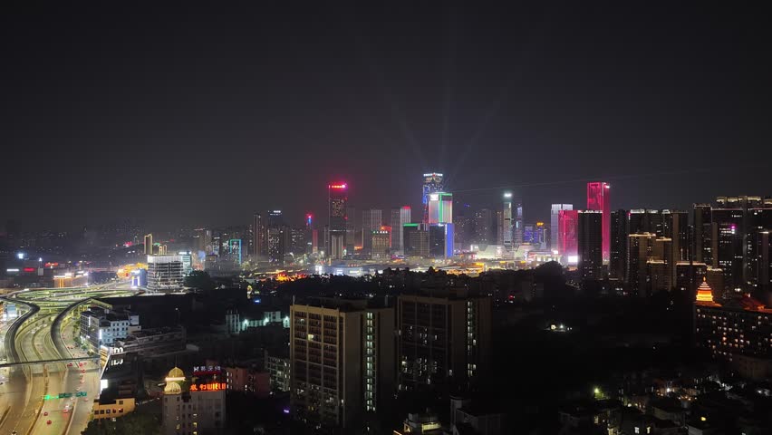 Aerial drone night view illuminated modern city skyline with skyscrapers buildings. Urban architecture, business center scenery night. Metropolitan landscape glowing lights. Twilight town travel.