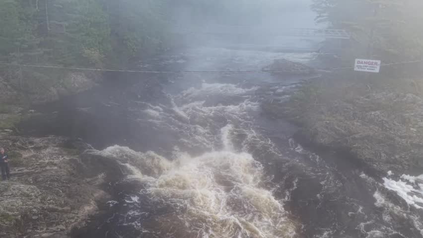 Moving upstream over foot bridge on a cold and foggy spring morning in Old Town, Maine 