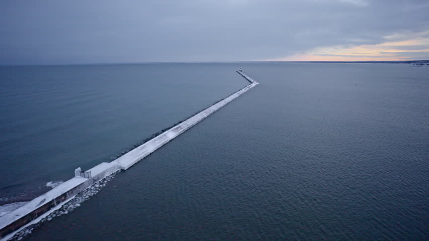 Aerial drone shot gliding above a winter-covered breakwater on the shores of Lake Superior.