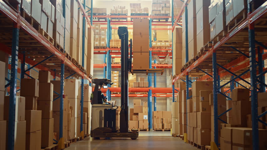 Retail Warehouse full of Shelves with Goods: Electric Forklift Truck Operator Lifting Pallet with Cardboard Box on a Shelf. Working in Logistics Storehouse Product Logistics and Delivery Center