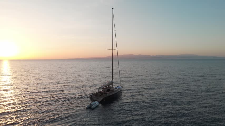 Aerial view of sailboat anchored at sea near Sardinia at sunrise, calm water scene