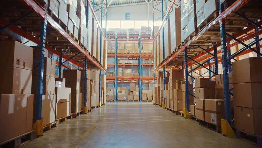 Huge Retail Warehouse Aisle With Racks Full of Cardboard Boxes Holding Consumer Goods. E-commerce Distribution Center Preparing Online Shopping Order Packages for Delivery. Dolly Zoom Walkthrough View