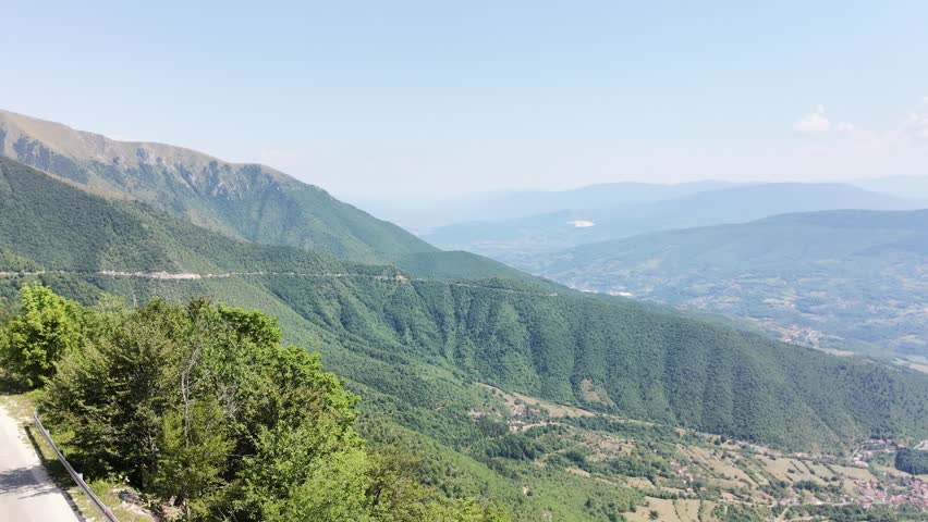 Scenic mountain roads winding through lush green hills under daylight. Peaceful natural landscape with forested slopes and rural roads, capturing the beauty of mountain travel and outdoor adventure.