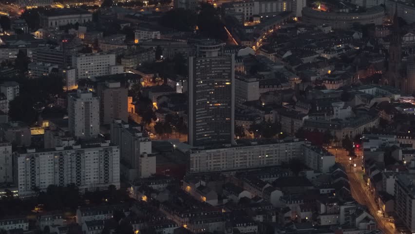 Aerial view of the illuminated city skyline of Mulhouse featuring residential buildings and street lights at night in Mulhouse, Grand Est, France.