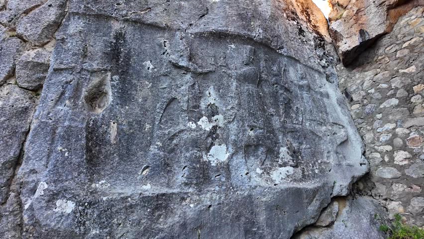 Weathered rock reliefs show a procession of Hittite deities carved into large stone walls at the Yazılıkaya open-air sanctuary.