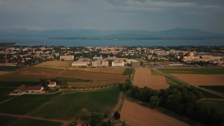 Aerial view of the town of Nyon with surrounding agricultural fields and Lake Geneva in the background in Nyon, Vaud, Switzerland.