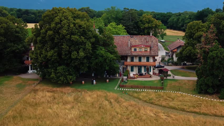 Aerial view of Domaine de Belle-Ferme surrounded by lush trees and fields in Bogis-Bossey, Vaud, Switzerland.