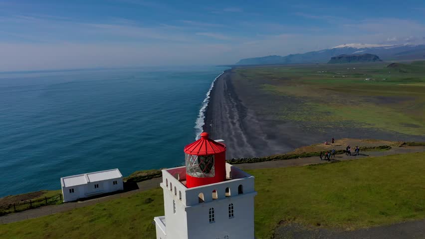Aerial view of Dyrholaey lighthouse overlooking the black sand beach and coastline in Vik, Myrdalshreppur, Iceland.