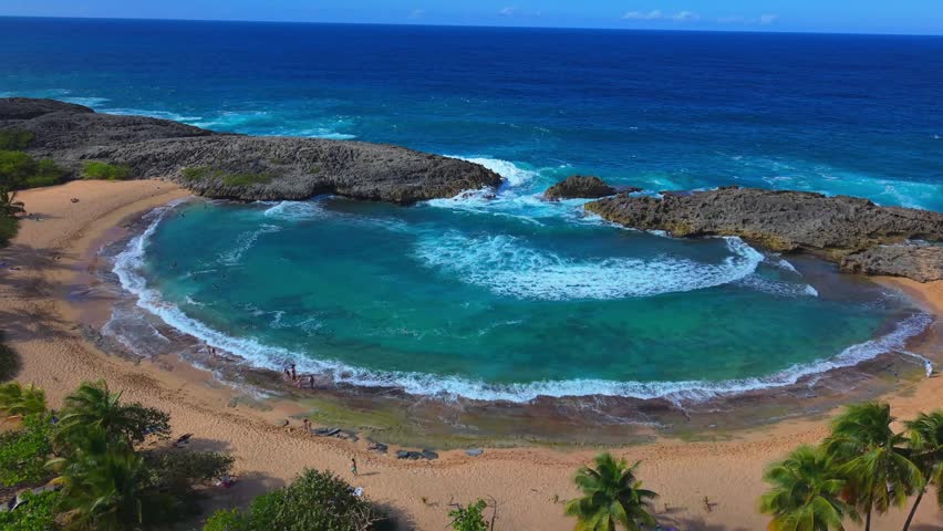 An aerial landscape shot highlights the rugged coral reefs surrounding the popular swimming cove at Mar Chiquita, Puerto Rico.