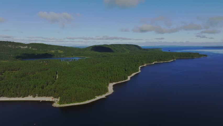 Aerial view of Koli National Park with dense forests and rocky shoreline along the deep blue waters of Lake Pielinen in Lieksa, North Karelia, Finland.