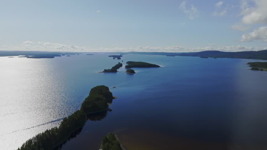 Aerial view of the expansive Pielinen lake with forested islands and calm blue water under a clear sky in Koli, Lieksa, North Karelia, Finland.