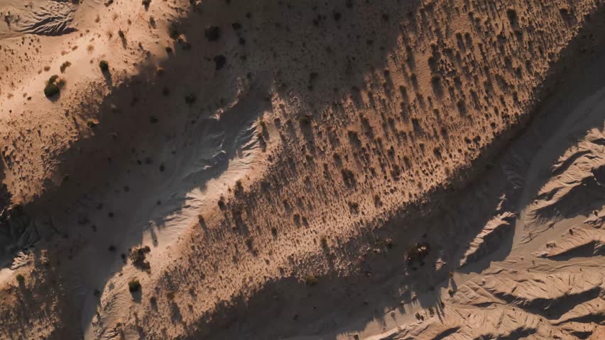 Aerial view of Valles Calchaquies desert landscape with sparse vegetation and dramatic shadows in San Carlos, Salta, Argentina.