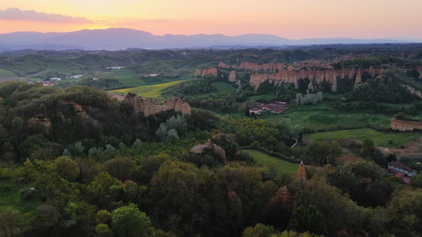 Aerial view of the unique geological formations of Le Balze del Valdarno at sunset with rolling hills and lush greenery in Piantravigne, Tuscany, Italy.