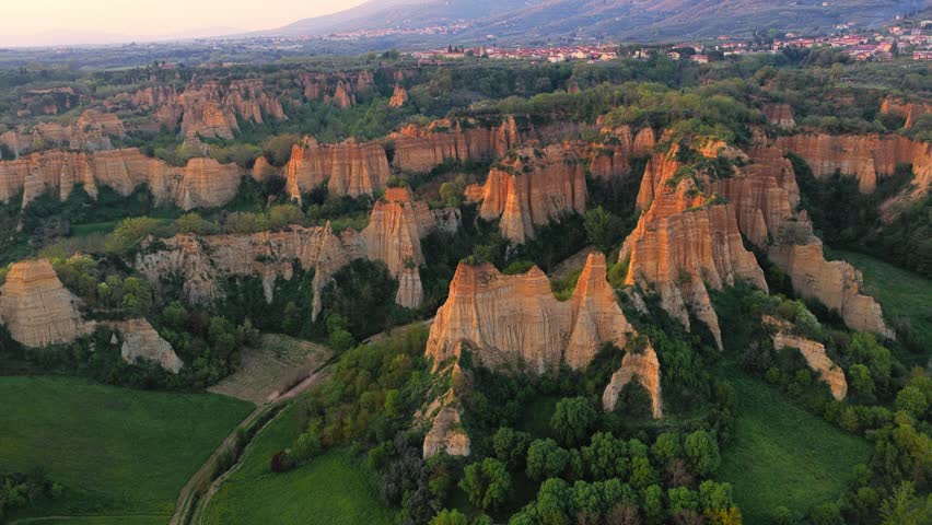Aerial view of the dramatic eroded clay cliffs of Le Balze del Valdarno at sunset, with lush greenery and rolling hills in Piantravigne, Tuscany, Italy.