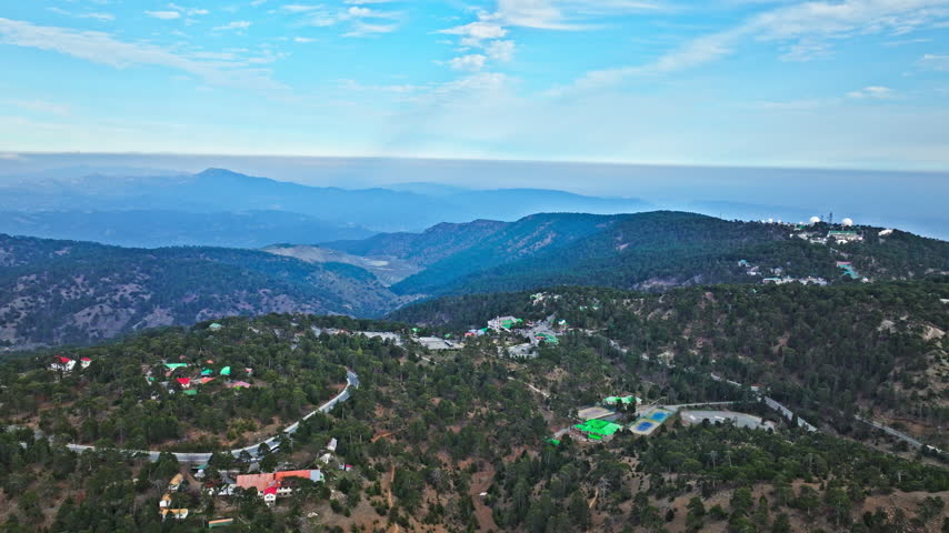 Wide aerial view from Mount Olympus in Cyprus. Blue mountain ranges, deep valleys and forested hills create a dramatic Troodos panorama.