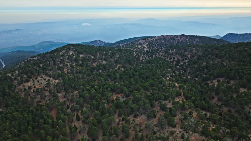 Drone view of Mount Olympus in the Troodos Mountains, Cyprus. Pine forests, rolling hills and mountain ridges create a peaceful natural landscape.