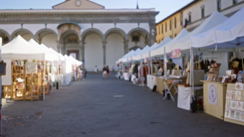 Defocused artisan market stalls in florence with soft bokeh in a historic square background; background backplate copyspace template.