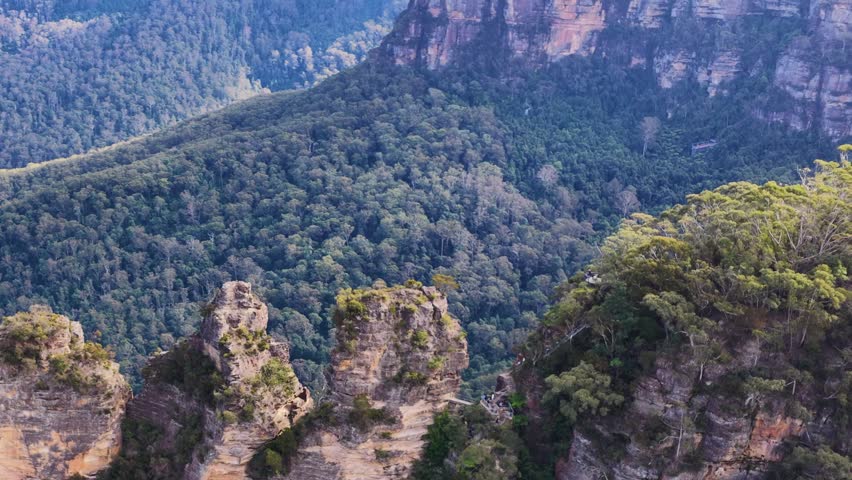 Wide shot of Three Sisters sandstone peaks overlooking lush Jamison Valley in Australia.