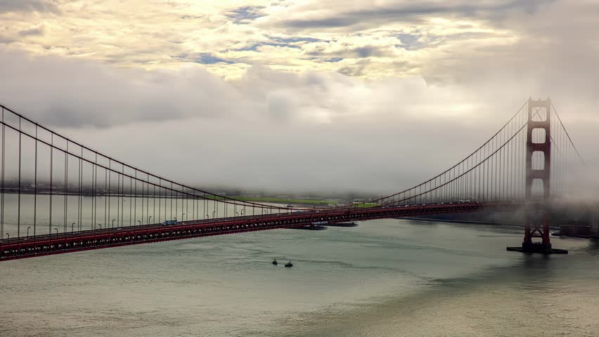 View of the iconic Golden Gate Bridge shrouded in thick fog over the bay with calm water below San Francisco, California, United States.