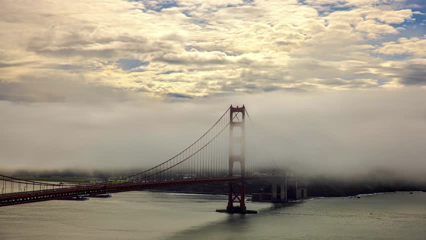 View of Golden Gate Bridge partially obscured by thick fog over the bay with cloudy sky San Francisco, California, United States.