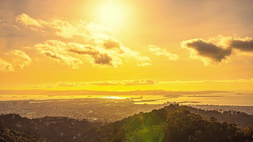 View of the San Francisco skyline during golden hour with the bay reflecting the warm sunset light over the hills in San Francisco, California, United States.
