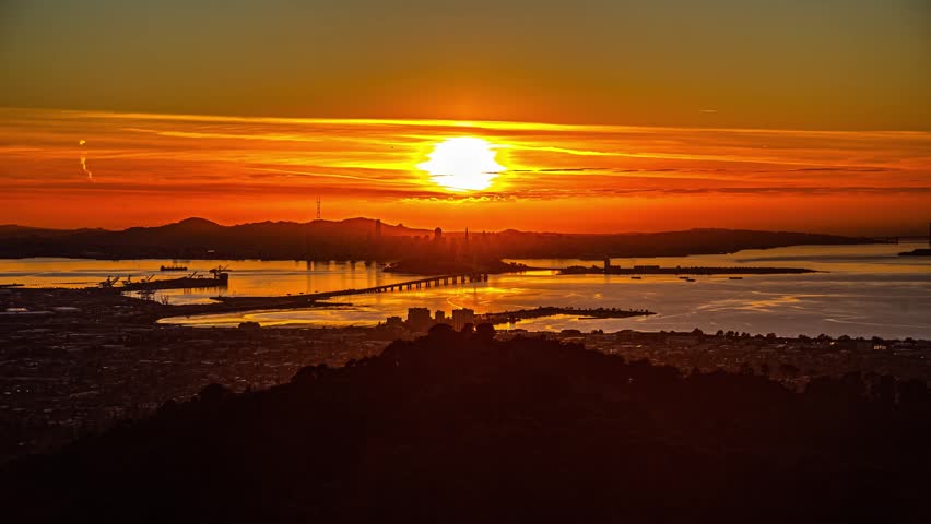 View of the San Francisco skyline silhouetted against a vibrant orange sunset over the bay, San Francisco, California, United States.