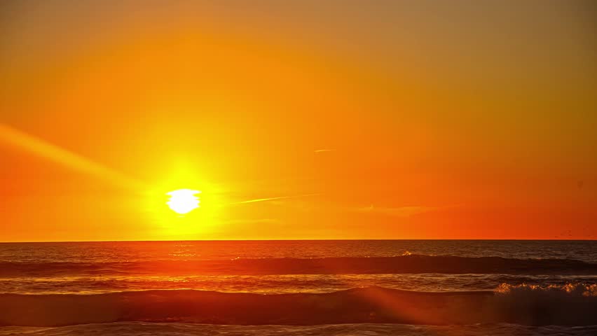 View of a vibrant sunset over the Pacific Ocean with golden light reflecting on the water in San Francisco, California, United States.