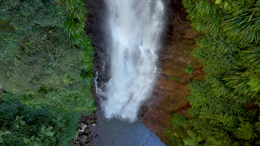 Top-down drone shot of a waterfall flowing over cliffs into a pool in Binna Burra.