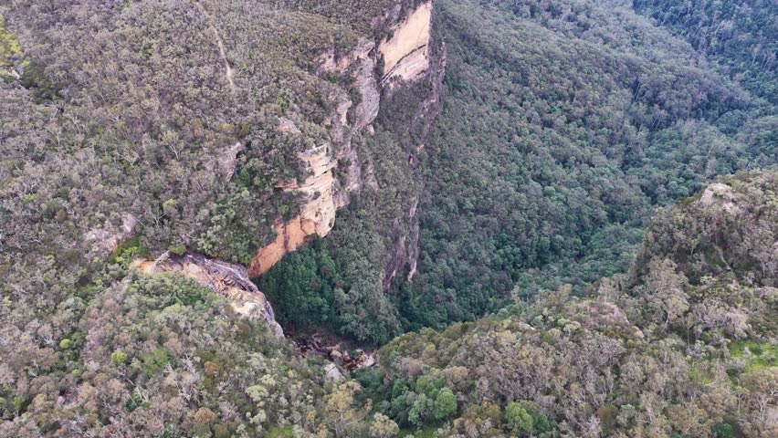 Aerial drone shot over sandstone cliffs and eucalyptus forest at Wentworth Falls, Blue Mountains.