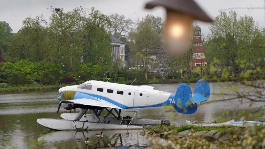 Vintage twinengine seaplane resting on floats, calm lake, overcast sky, Belgium zoo.