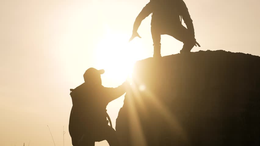 People climbing mountains at sunset