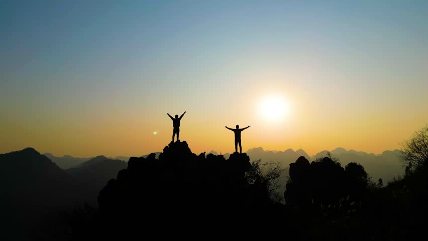People climbing mountains at sunset