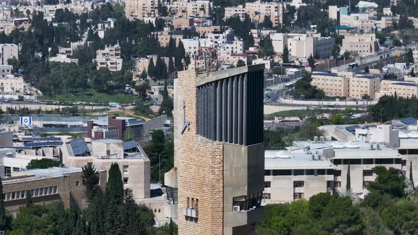 Detailed telephoto drone view highlighting the top of the Hebrew University observation tower on Mount Scopus with Jerusalem urban hills in background.