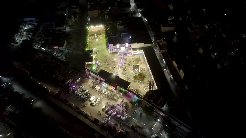 Aerial night view of a vibrant wedding celebration in Mumbai, India, featuring illuminated outdoor event grounds.