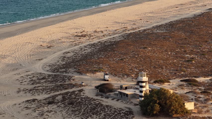 Aerial of Punta Arena lighthouse and camper van on the beach in La Ventana.
