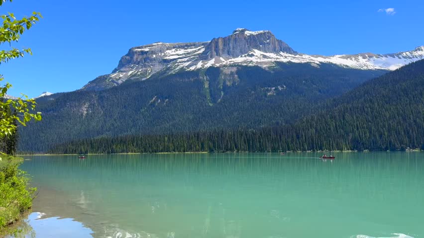 Beautiful view on the Emerald lake. Canada, Yoho National Park, Rocky Mountains. Beautiful mountain lake surrounded by evergreen trees and snow-capped peaks, featuring boats on the tranquil water