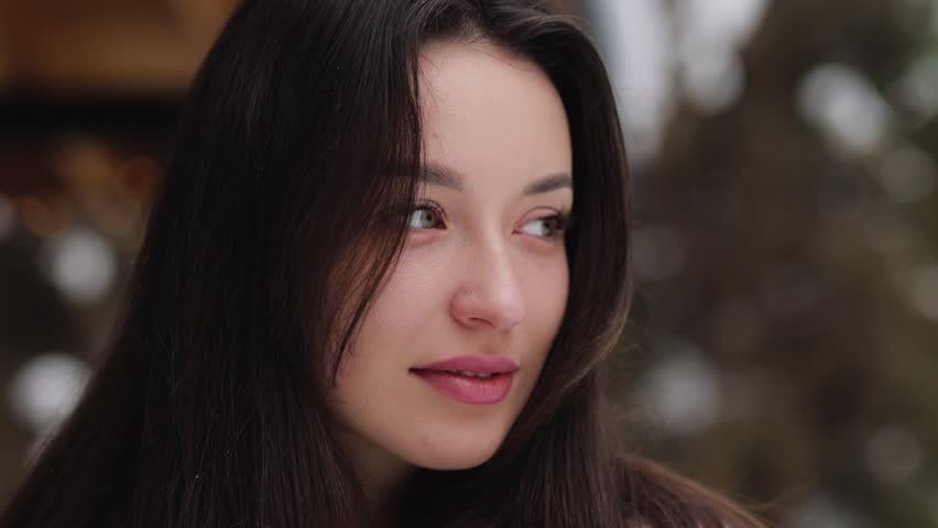 Close up portrait of a beautiful young woman with natural makeup making eye contact outdoors in winter