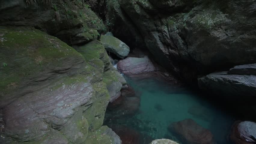 Clear blue water flows into small rocky natural pool in Shikoku, Japan