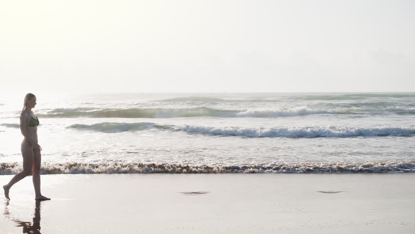 Confident young woman enjoying the ocean waves during a sunny summer day, celebrating freedom, confidence and a modern women