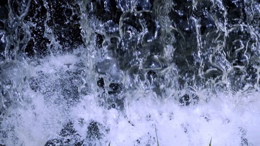 Scenic waterfall water flowing rapidly with swirling currents, splashes, and crystal clarity.