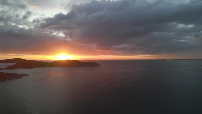 Sunset behind a small island in the distance as dark clouds move in.