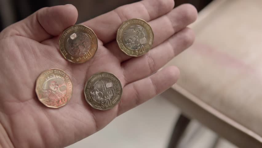 Closeup of hand holding Mexican fifty peso coins, highlighting everyday cash transactions, currency and personal finance in Mexico