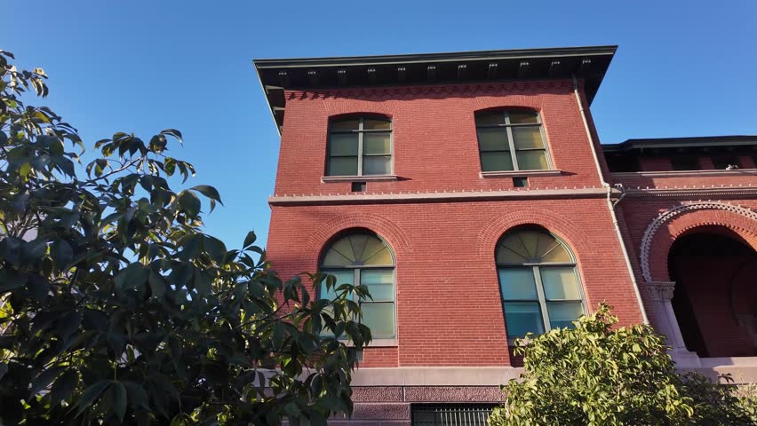 Detailed architectural view of the red brick Alameda City Hall. A historic landmark in California. Seen from a low angle against a clear blue sky on a bright sunny day