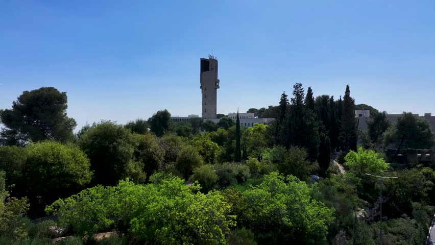 Ascending perspective above the Hebrew University observation tower revealing green Mount Scopus hillsides and distant valley views.