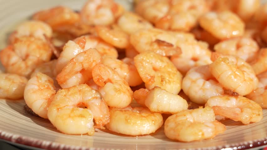Juicy fried shrimp rotate on a plate and display their golden surface. These crustaceans pair well with rice, salad or vegetables.
