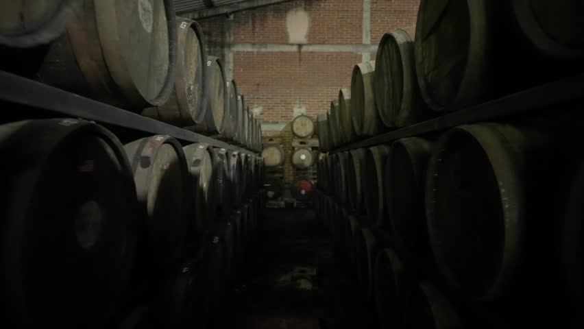 Long aisle of wooden barrels stored inside a rum aging warehouse, backdrop ready for text